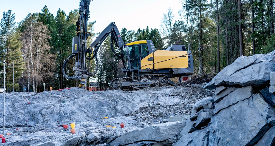 Borrigg för att spränga berg nära hus vid byggarbetsplats i skogsmiljö i Stockholm.