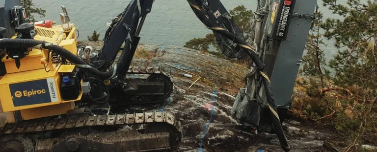 Bergspräckning Stockholm med borrigg på svårtillgänglig bergshäll vid vattennära miljö.