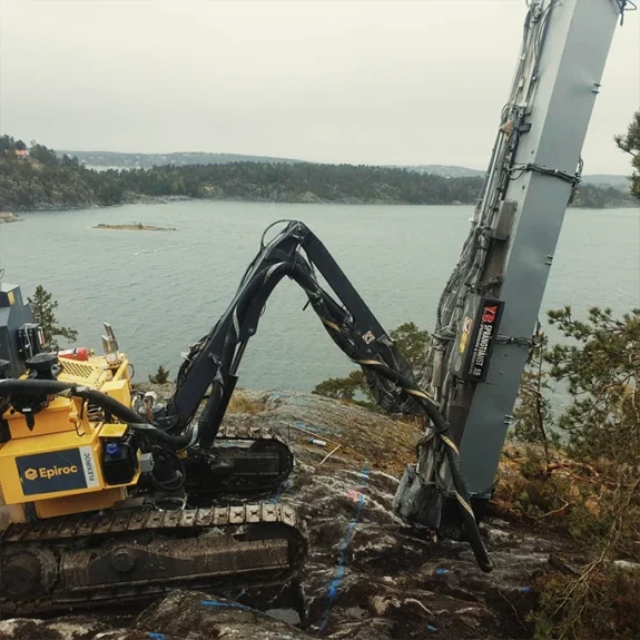 Bergspräckning Stockholm med borrigg på svårtillgänglig bergshäll vid vattennära miljö.