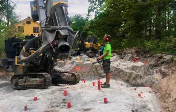 Bergsprängning Stockholm med borrigg och förberedda spränghål på byggarbetsplats